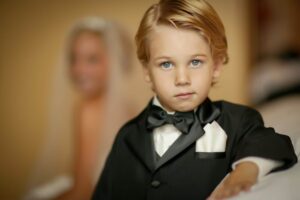 blue-eyed ring bearer with bride in background