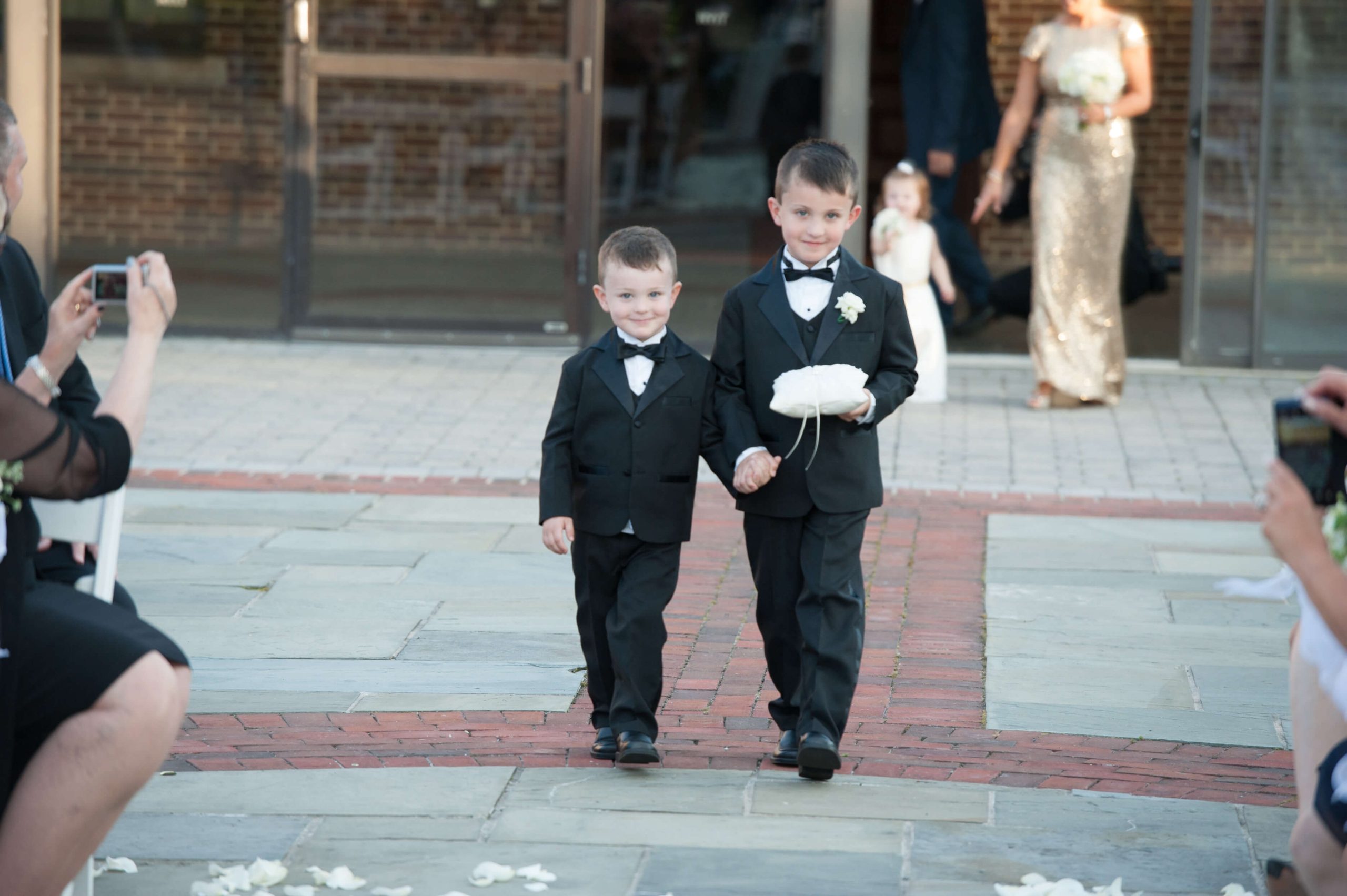 two boys in black tuxedos at wedding ceremony