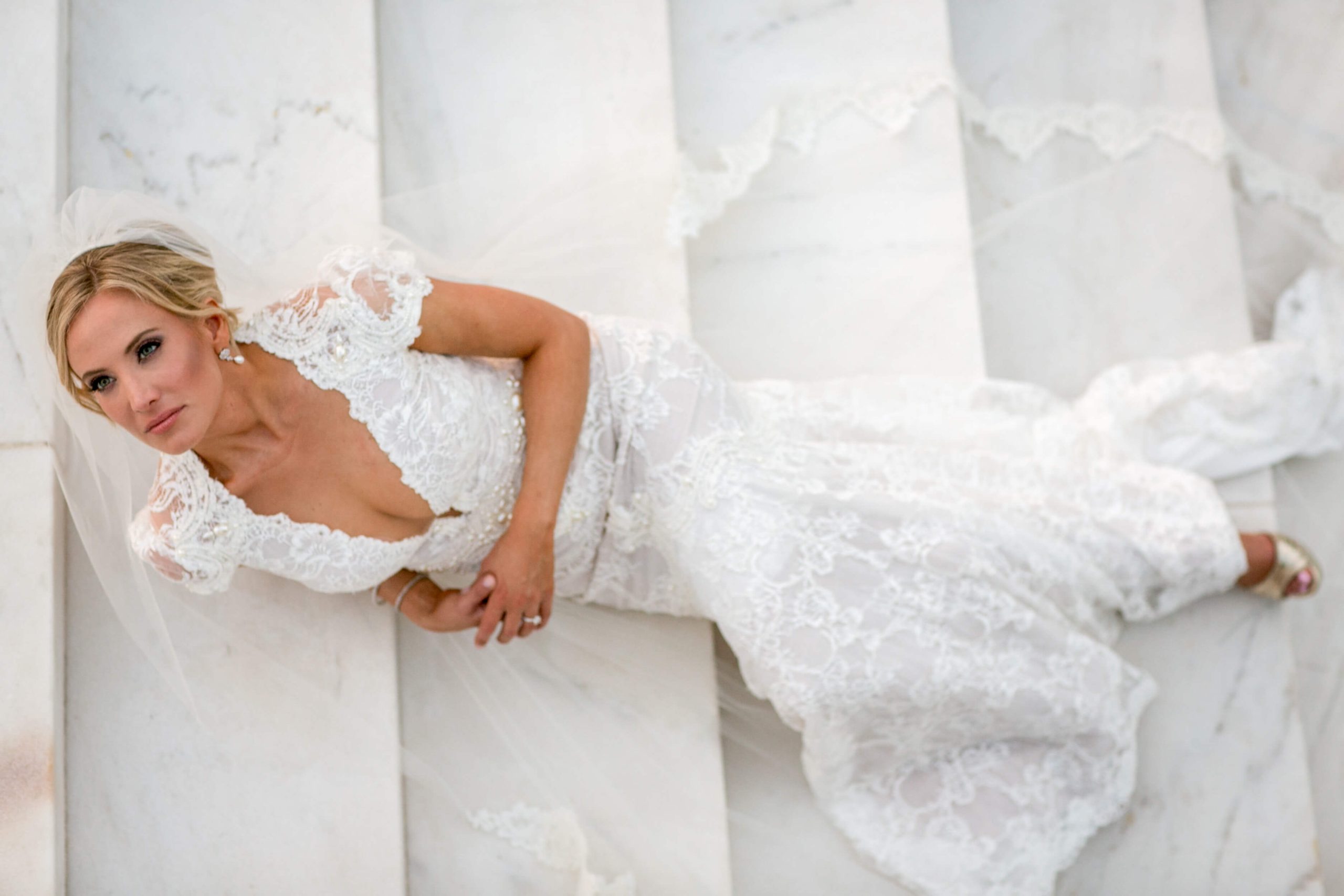 bride laying on white marble stairs