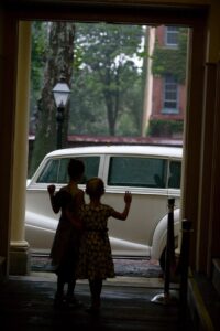 two children waving goodbye to vintage car