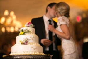 bride and groom kiss near wedding cake