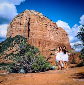 three women in white dresses hugging and laughing in Sedona desert