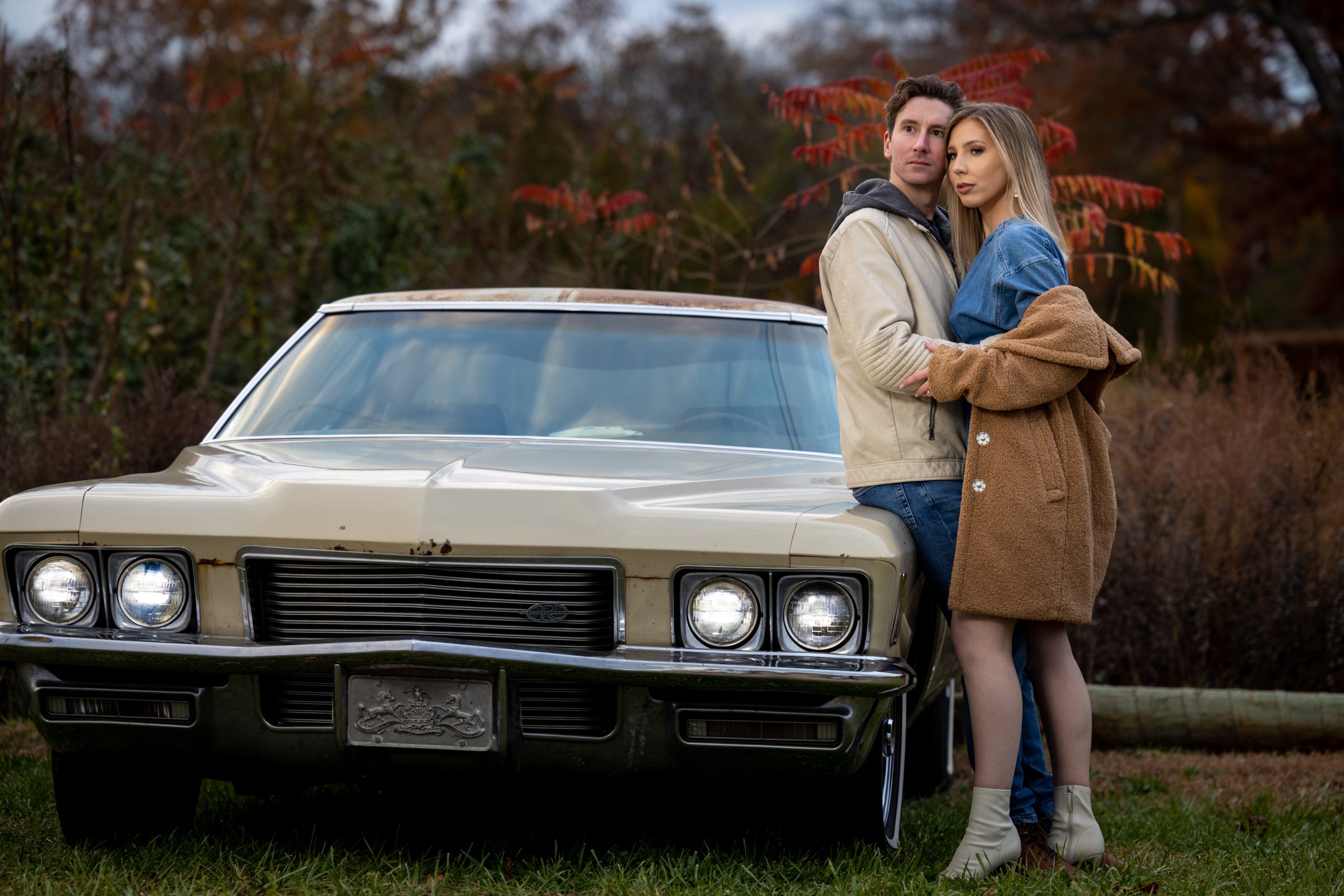 couple embracing with vintage buick riviera car during the Fall months