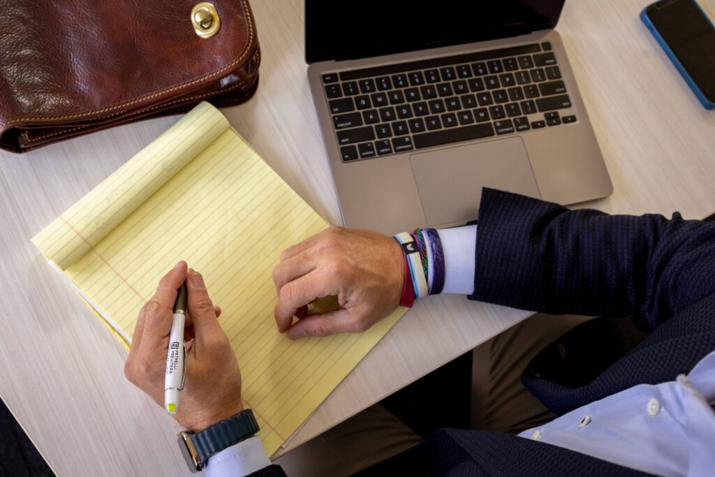 man writing on notepad on desk