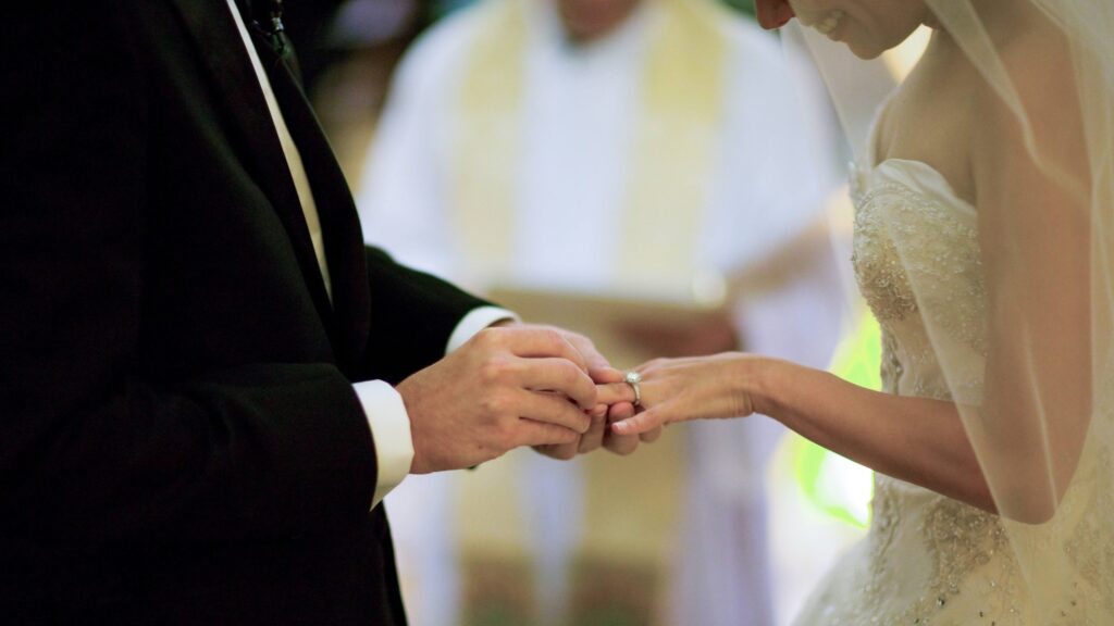 groom slides ring on bride's finger