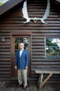 dick vermeil posing by private log cabin