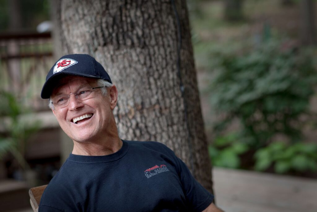 dick vermeil laughing in garden while wearing a kansas city chiefs hat