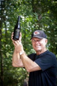 dick vermeil holding a syrah wine bottle