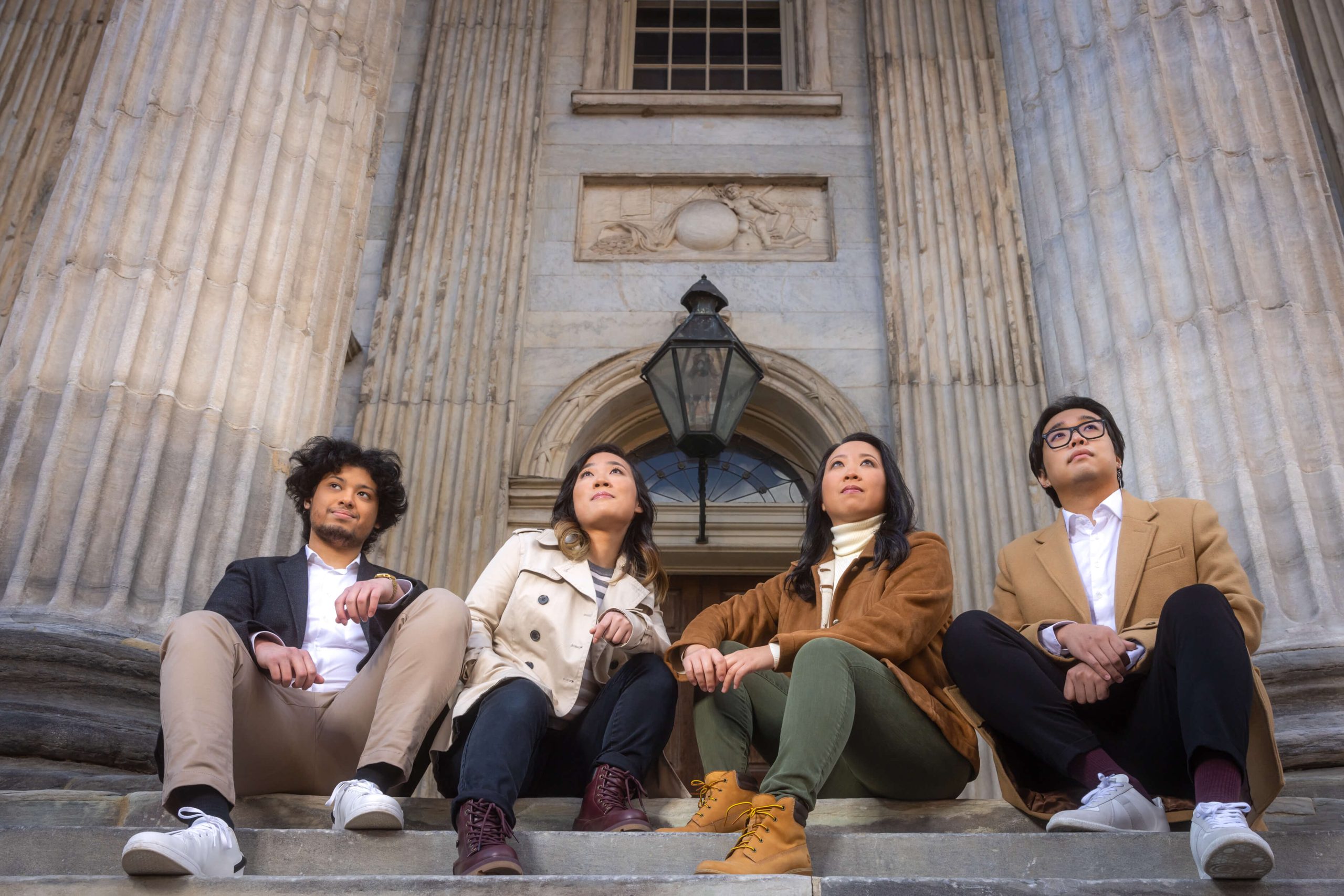 four people sitting at steps of historic American building