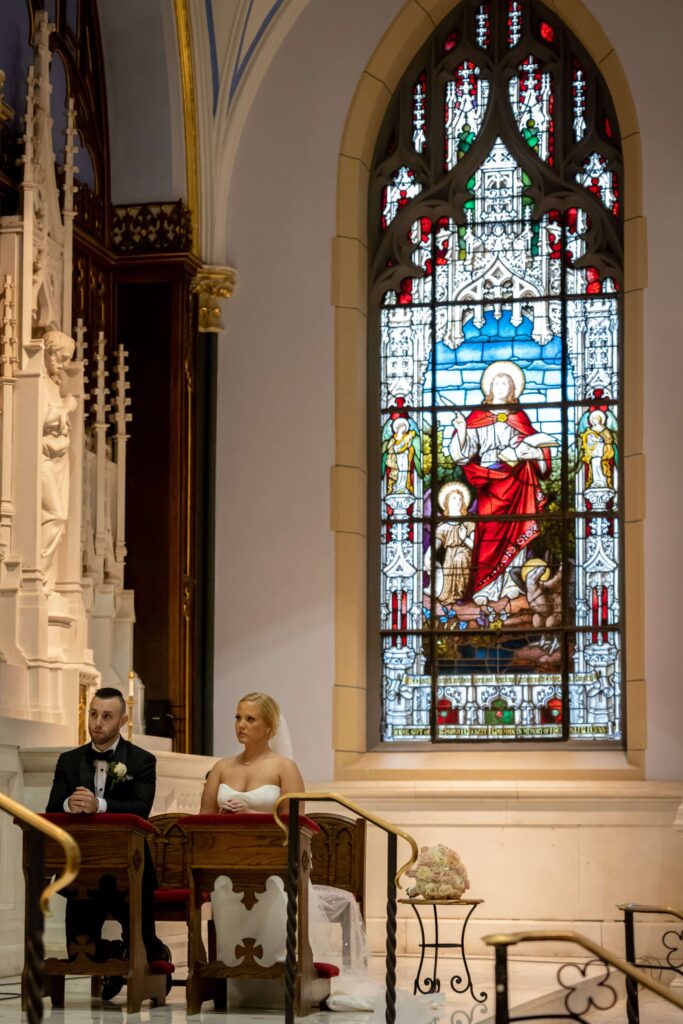 bride and groom kneel at catholic wedding ceremony