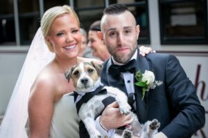 bride and groom hold dog on wedding day