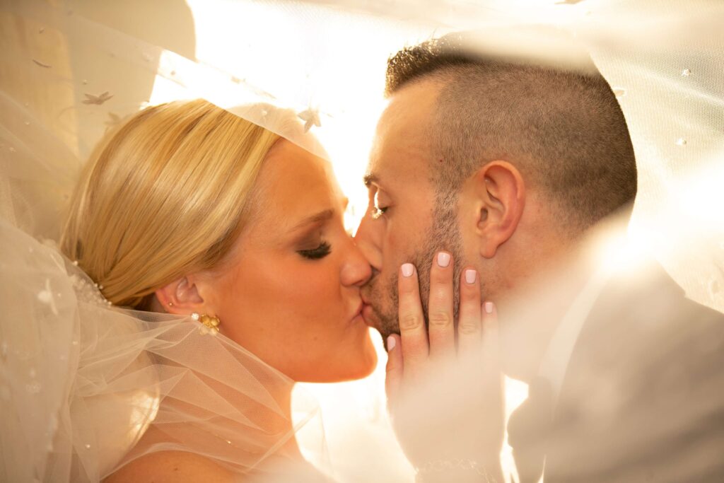 bride and groom kiss under wedding veil