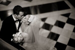 bride and groom kissing against black and white tiles