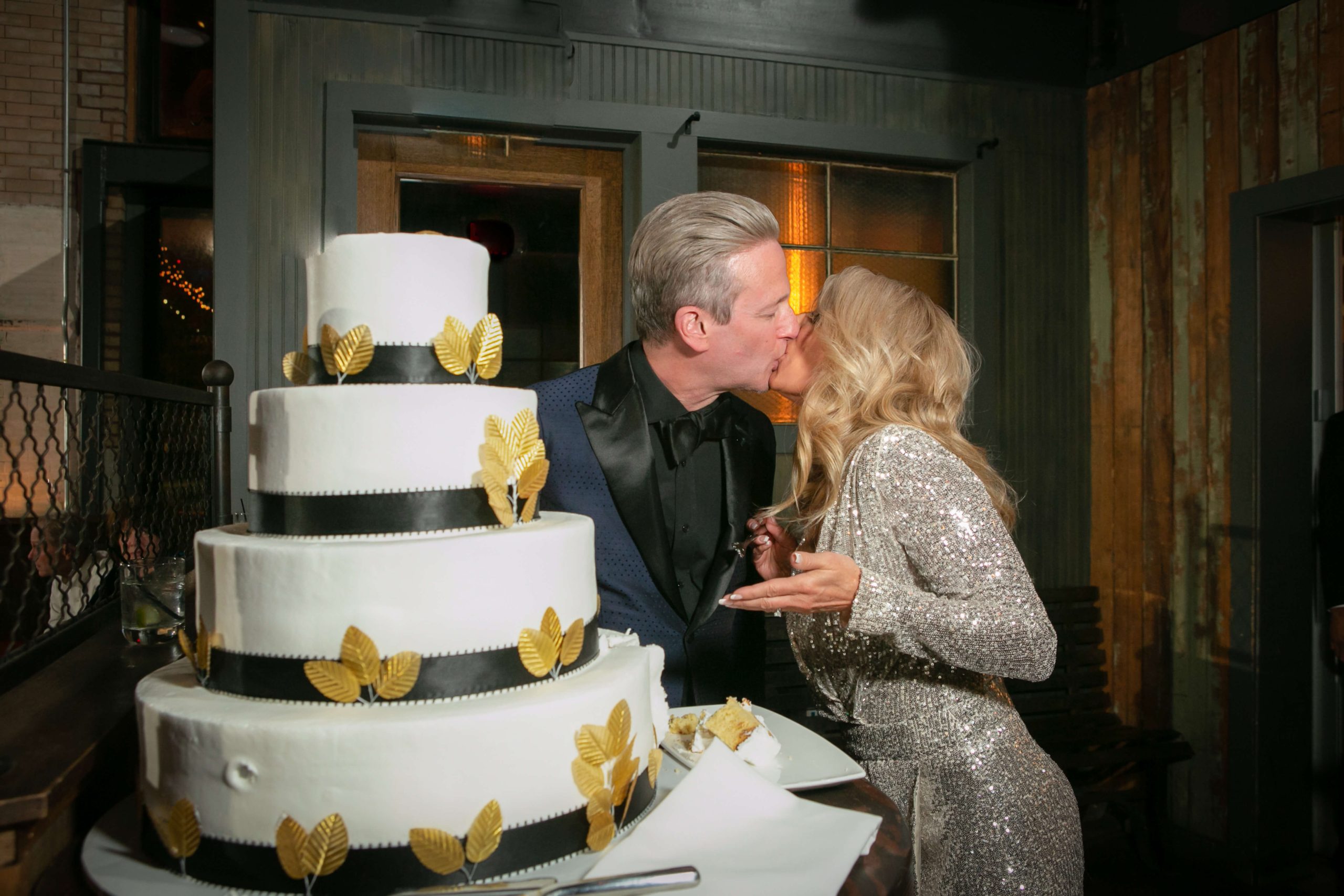 bride and groom kiss at wedding cake
