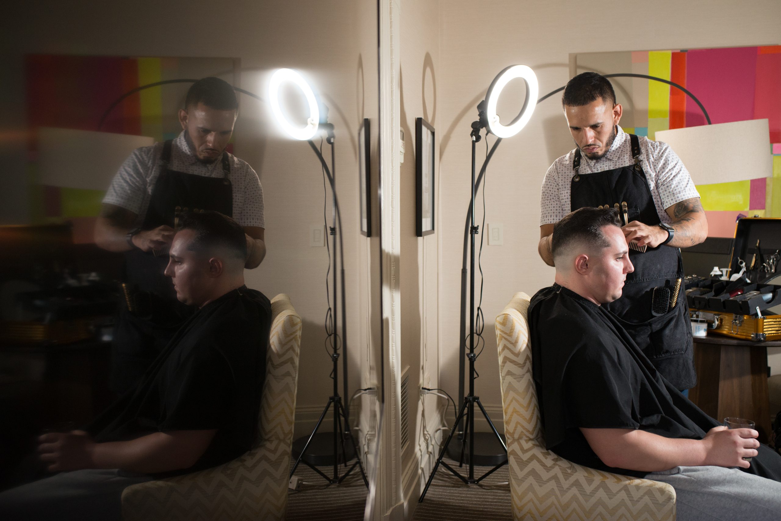 barber cuts man's hair with shaver and ring light