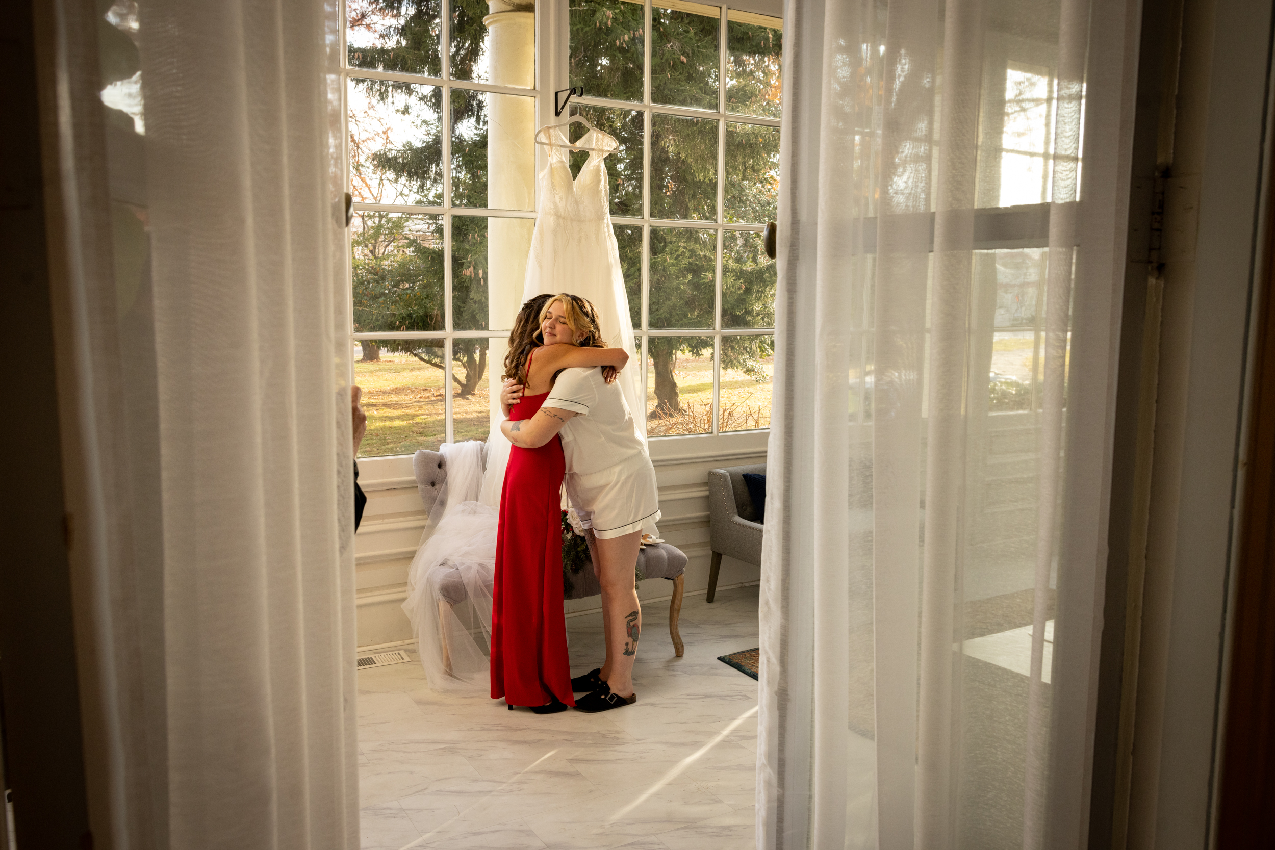 mother and bride hug at wedding dress in sunroom