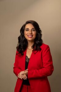 andriena botto in red blazer and clasping hands