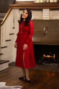 woman in red dress smiling in historic home by fire place