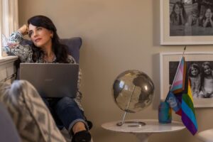 woman looking out window in family room with computer on lap