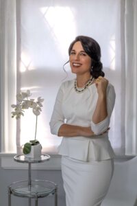 woman in white dress and room posing next to flowers