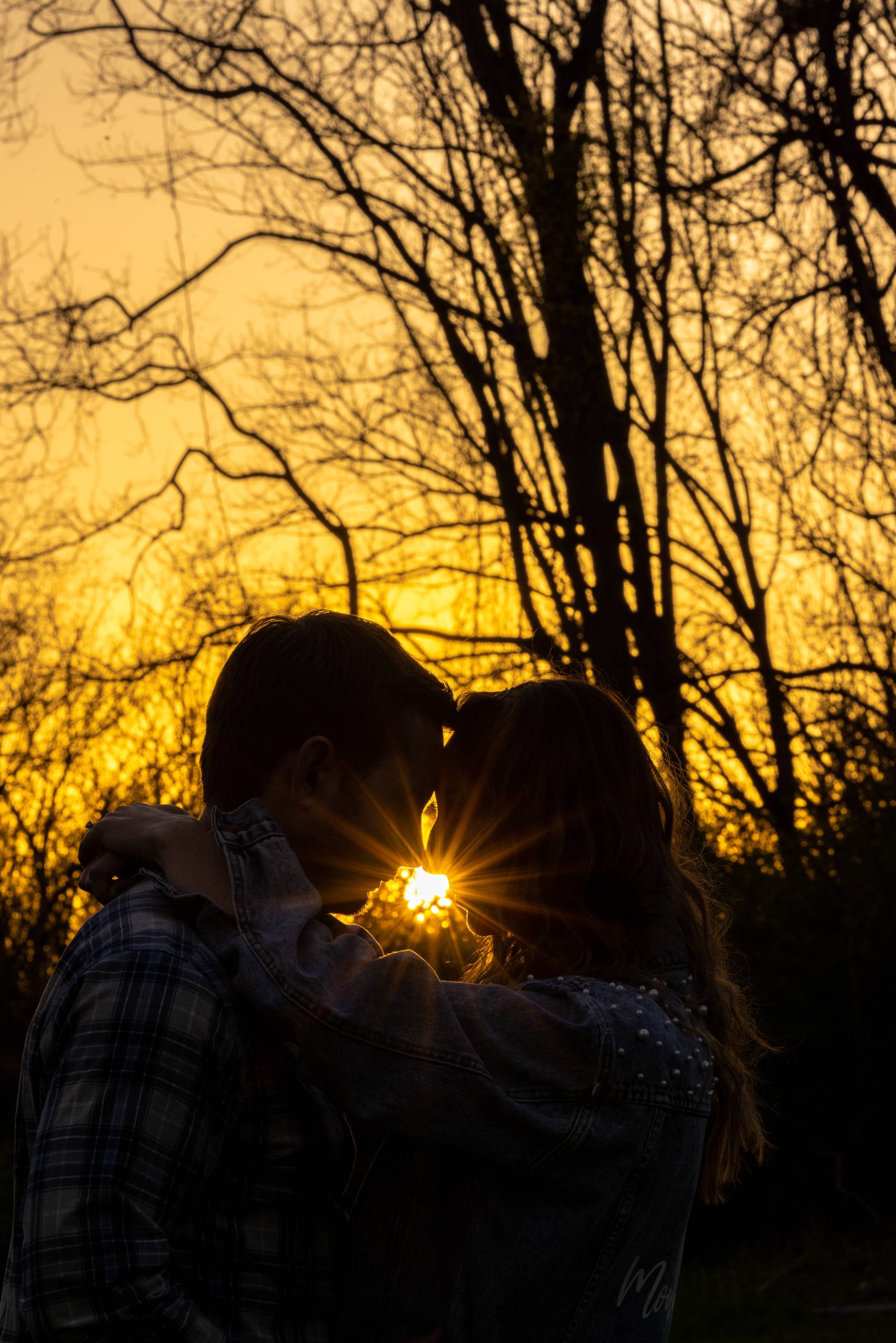 silhouette of man and woman touching foreheads with sunset