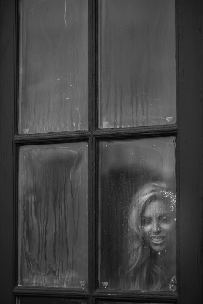 bride looks out of rainy window on wedding day