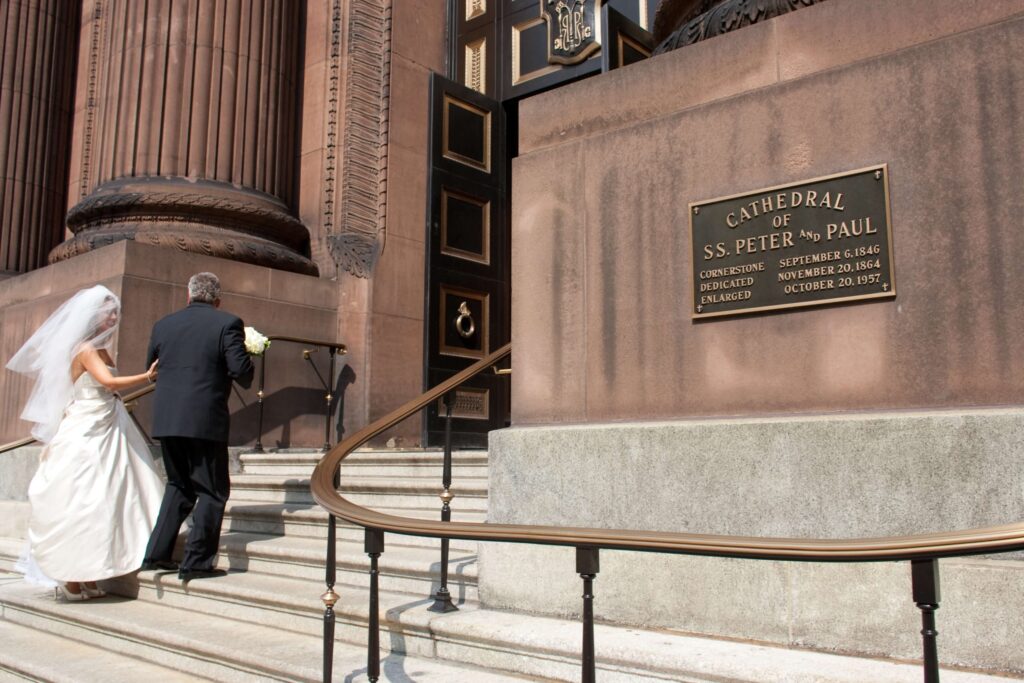 bride enters catholic church for wedding ceremony with father
