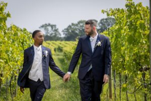grooms holding hands in wine vineyard