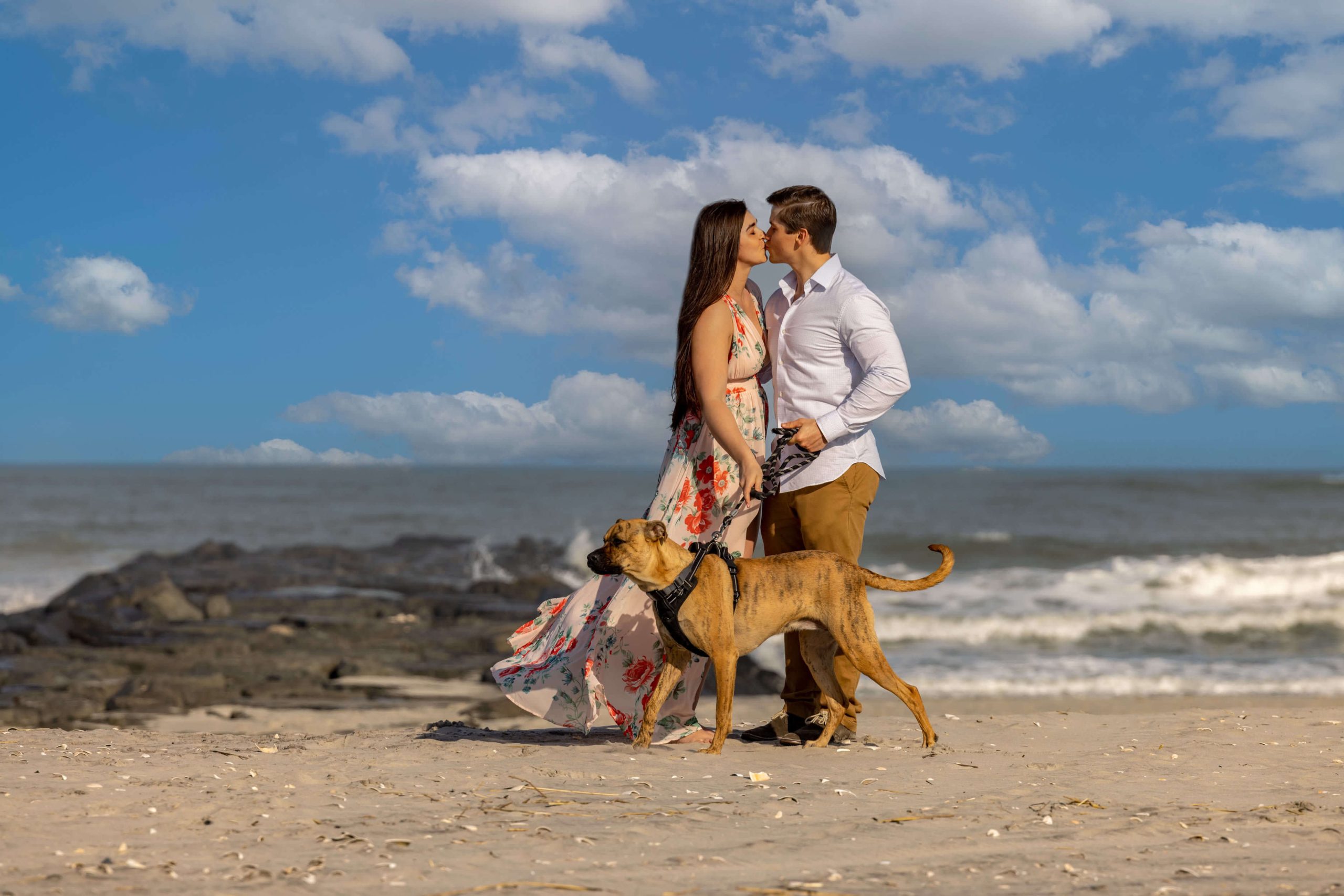 couple kissing on beach with dog