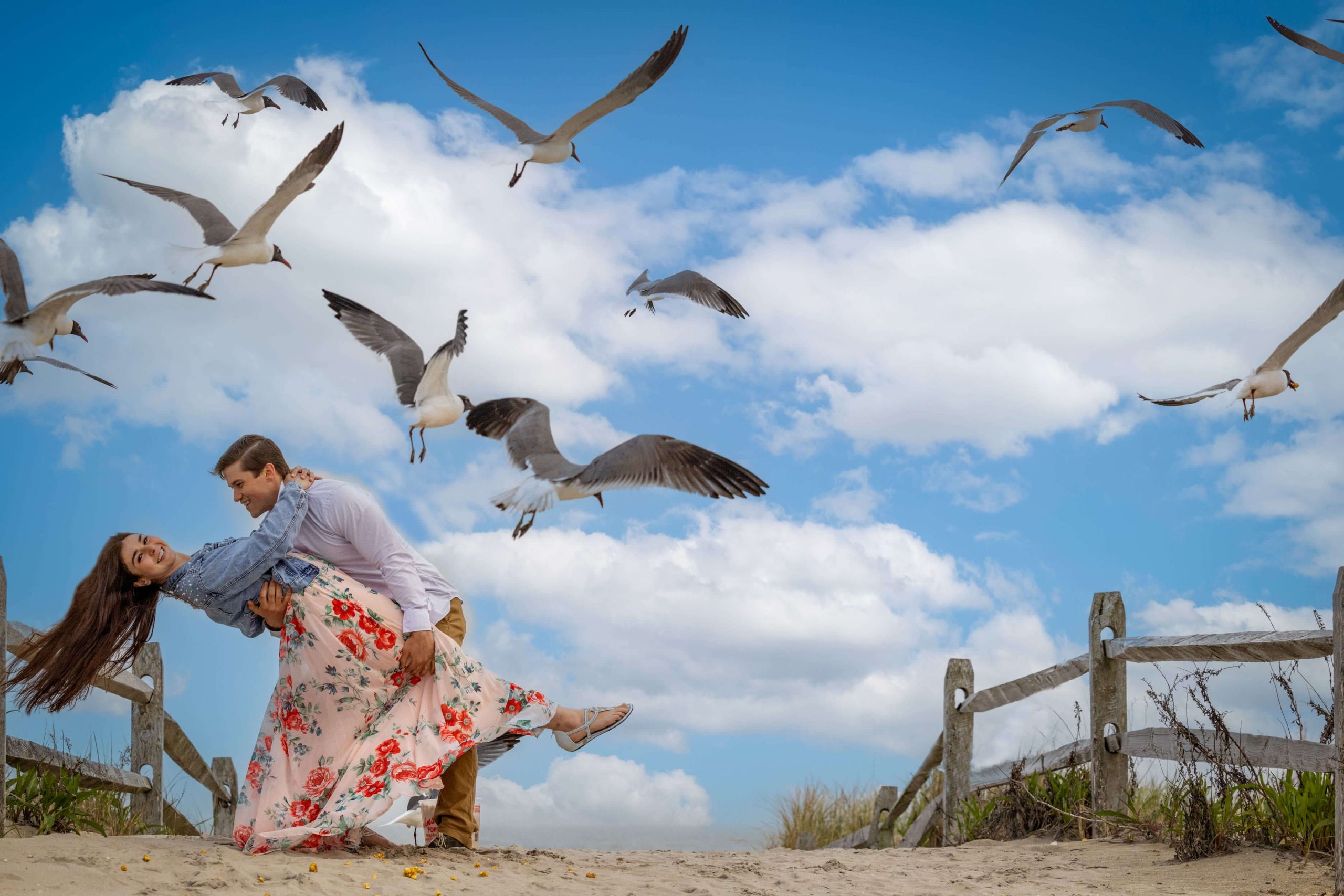 man dipping woman on beach as seagulls fly