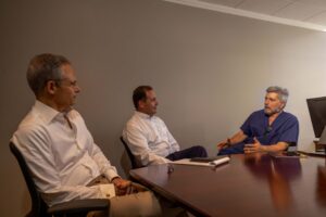 three men at conference table having a conversation