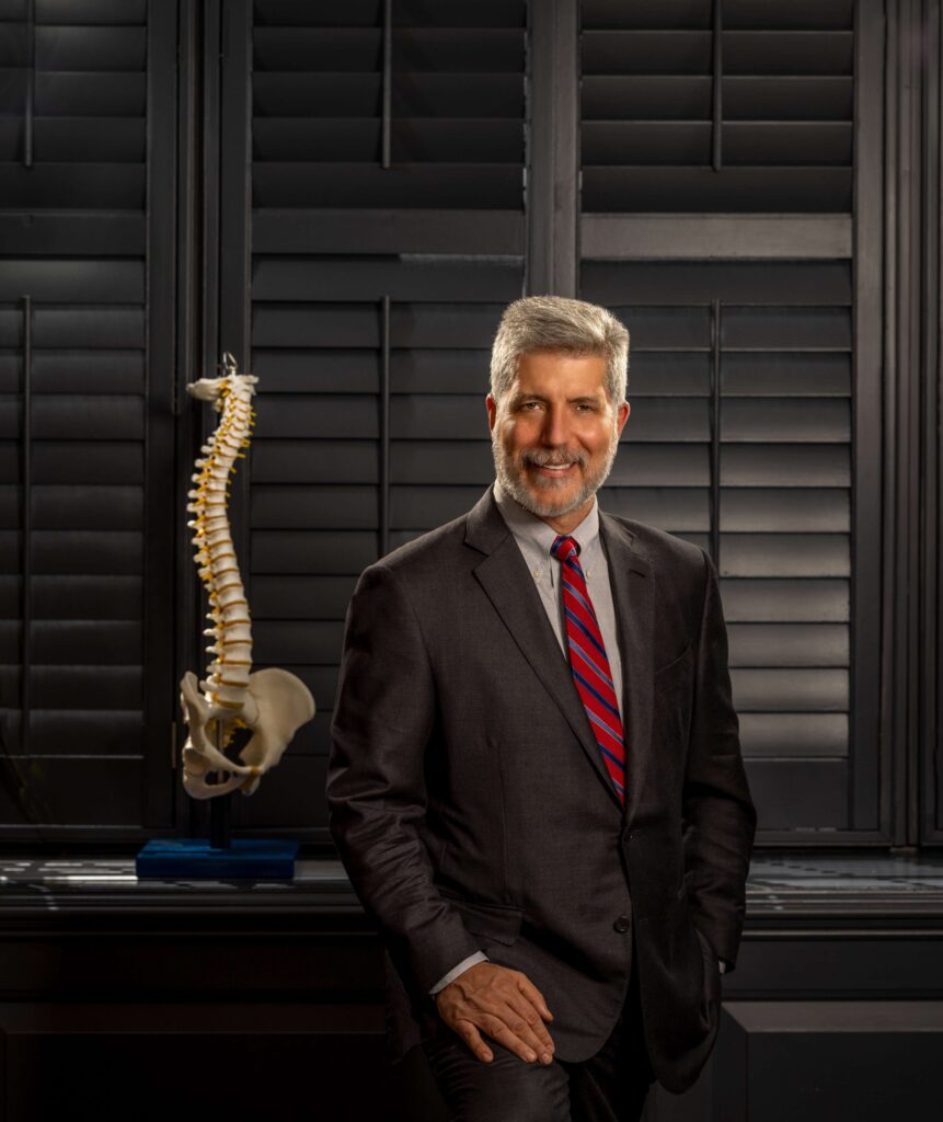 man in suit poses next to spine skeleton replica