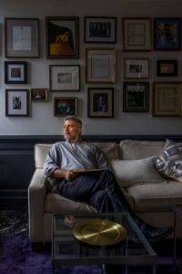 man on white couch looking out window