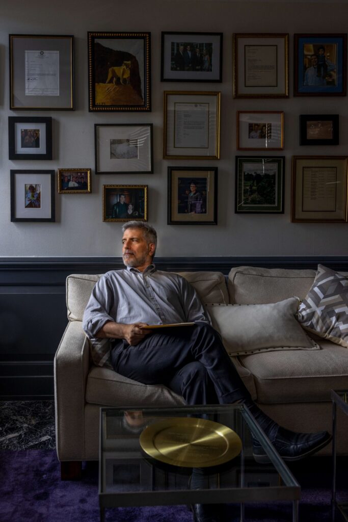 man on white couch looking out window