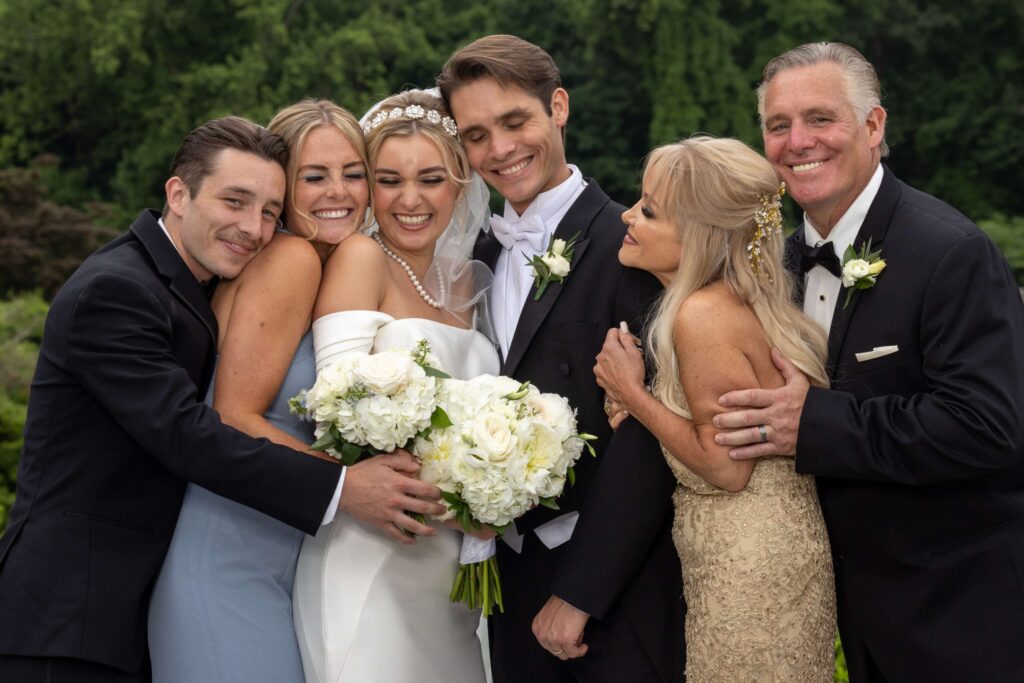 black tie bride and groom posing with family at outdoor wedding