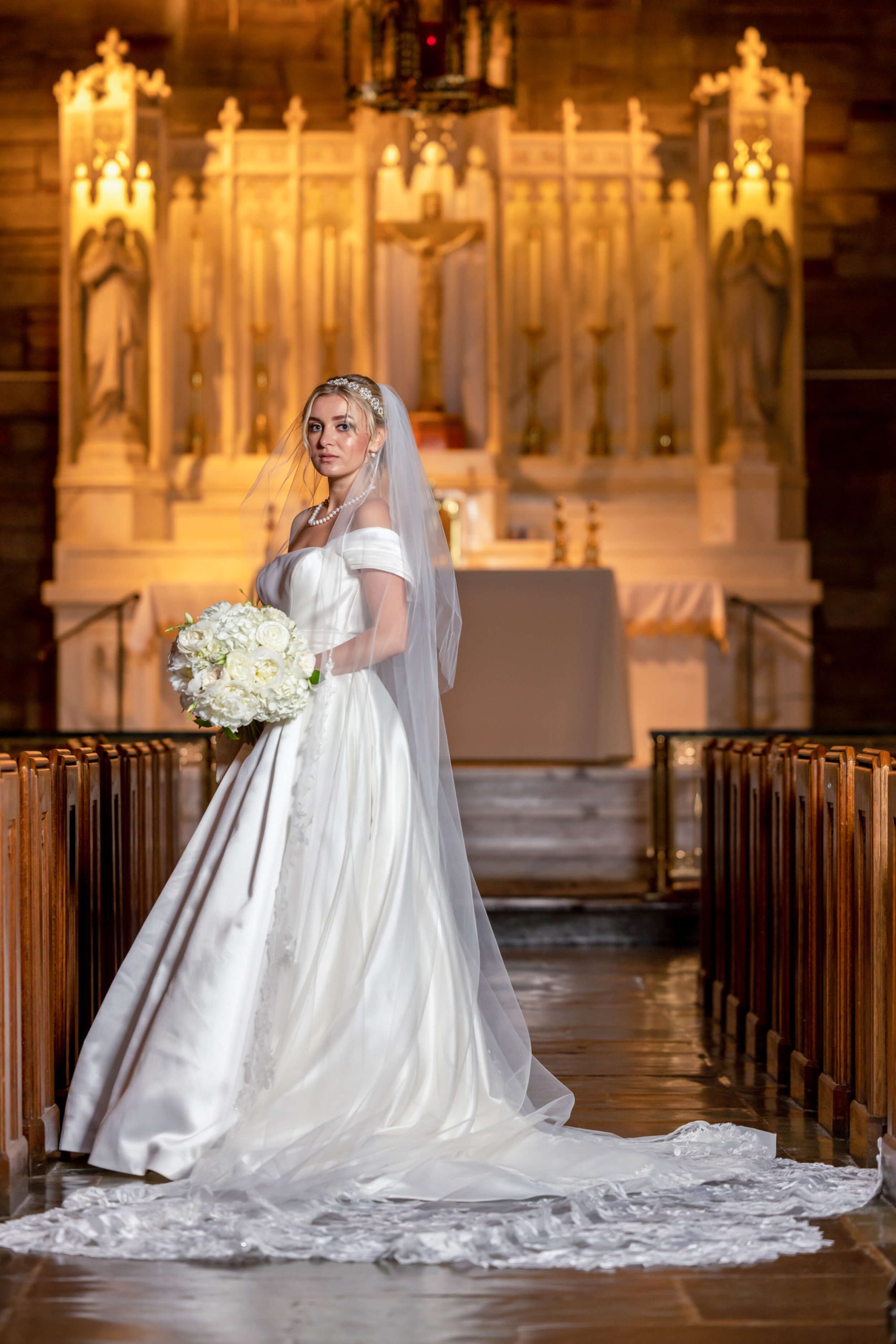 bride with white flower bouquet at altar in catholic church