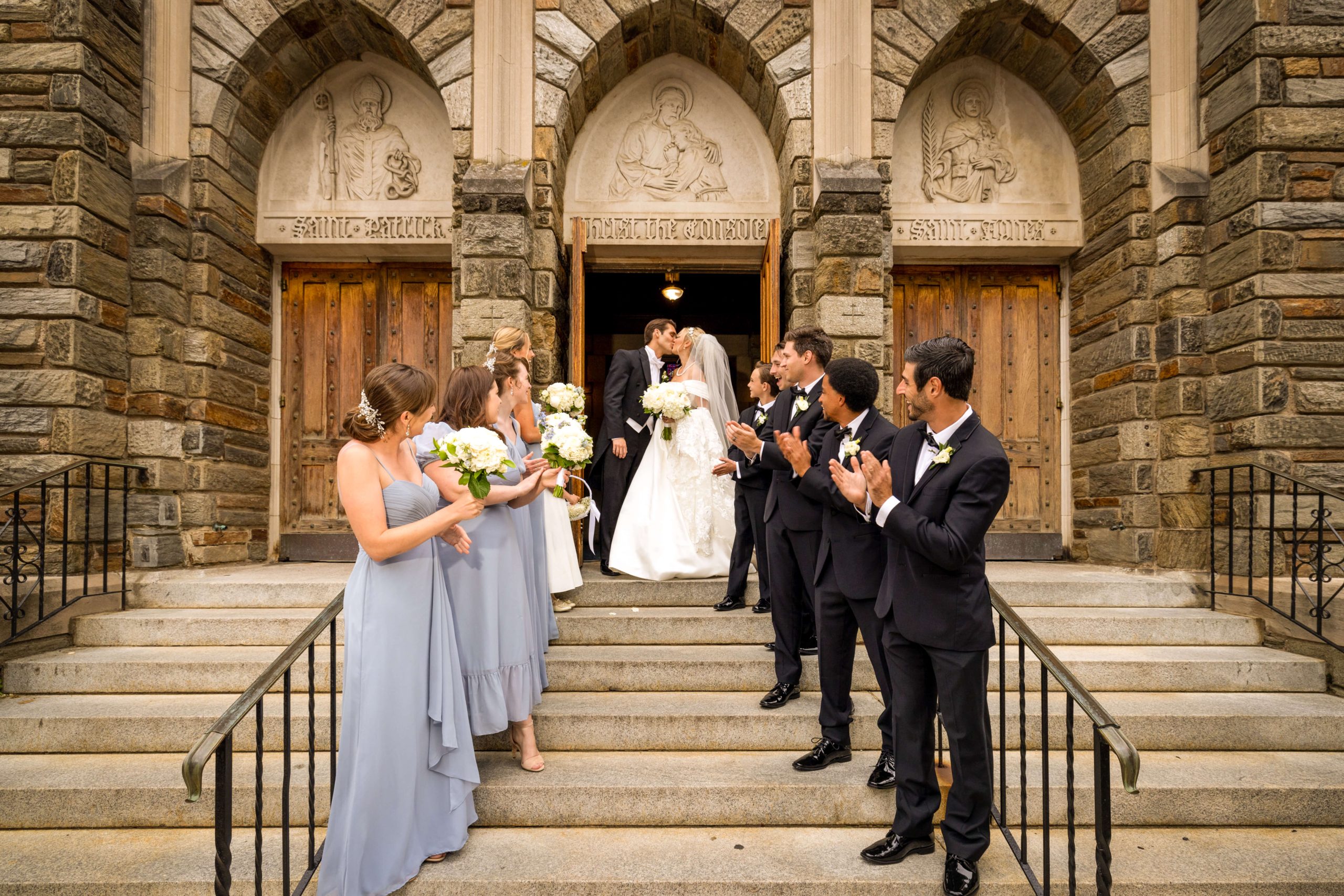 bride and groom kiss on outdoor stairs at catholic church