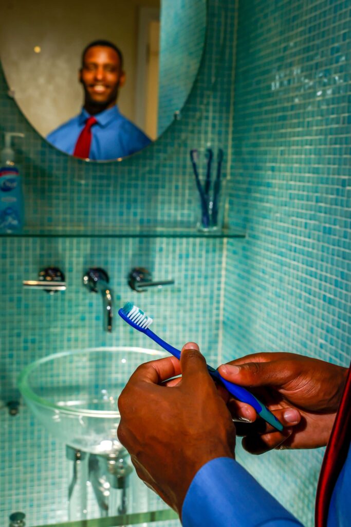 man brushing teeth in mirror in turquoise tile room