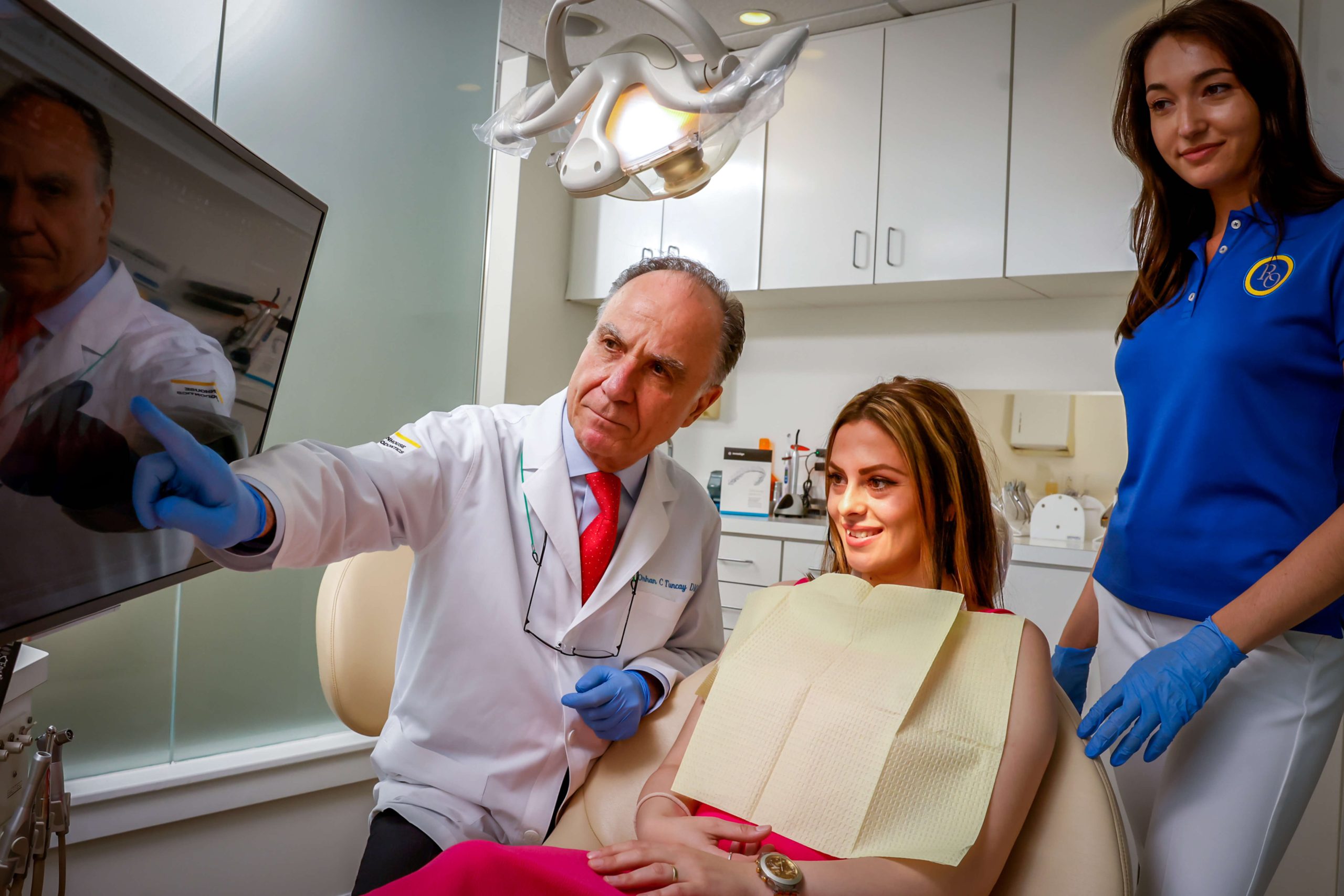 dentist pointing to monitor with patient and assistant in operating room