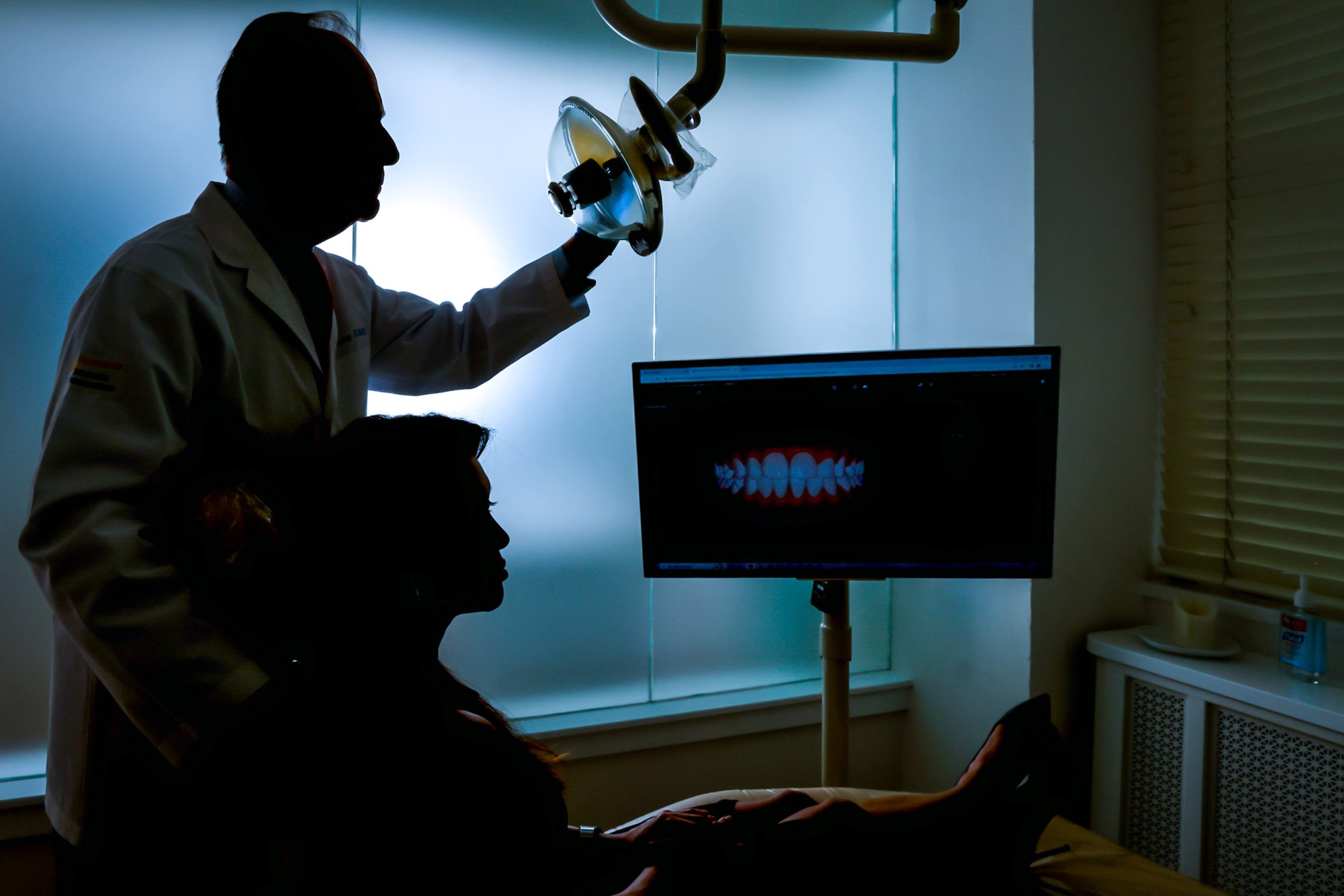 dentist in dark room with monitor and surgical light