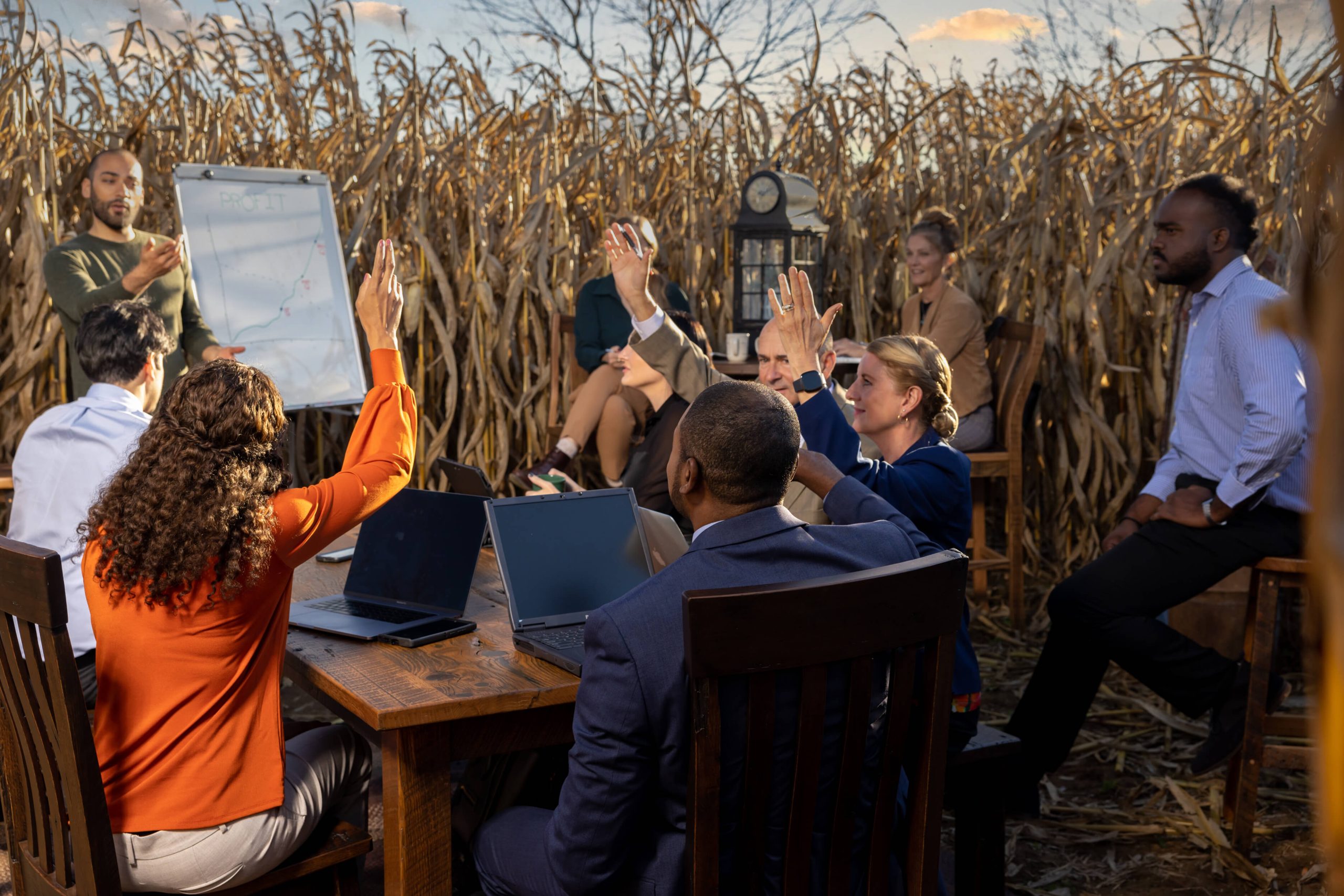businesspeople raising their hands at meeting in a cornfield