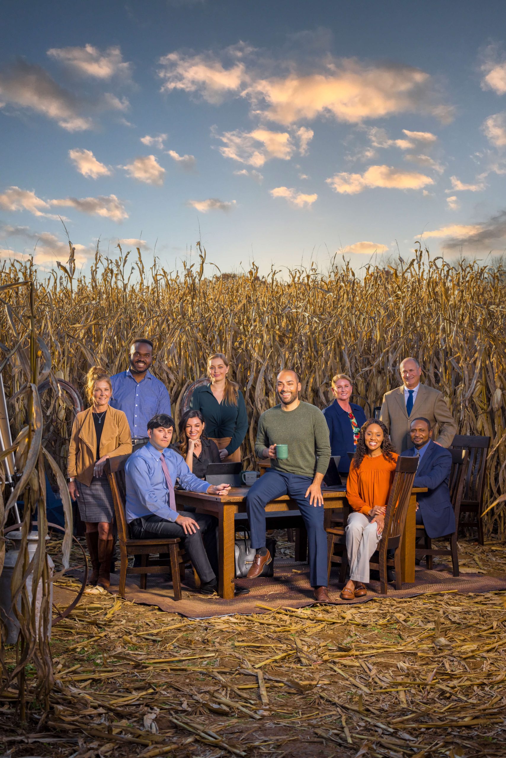 businessmen and women at conference table in cornfield