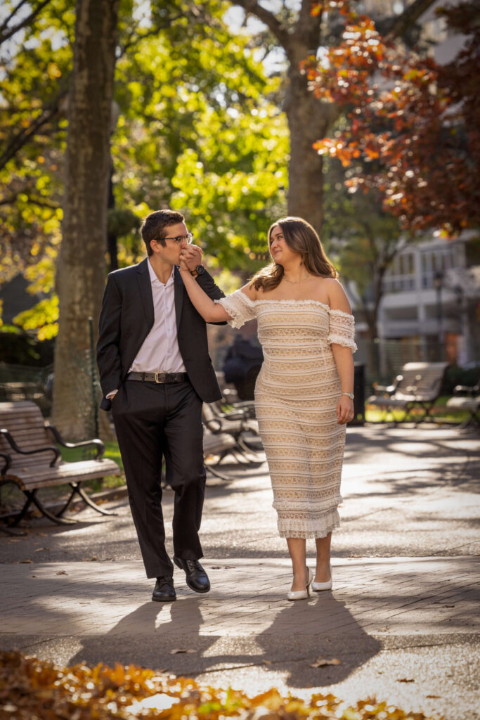 man kissing woman's hand while walking in park