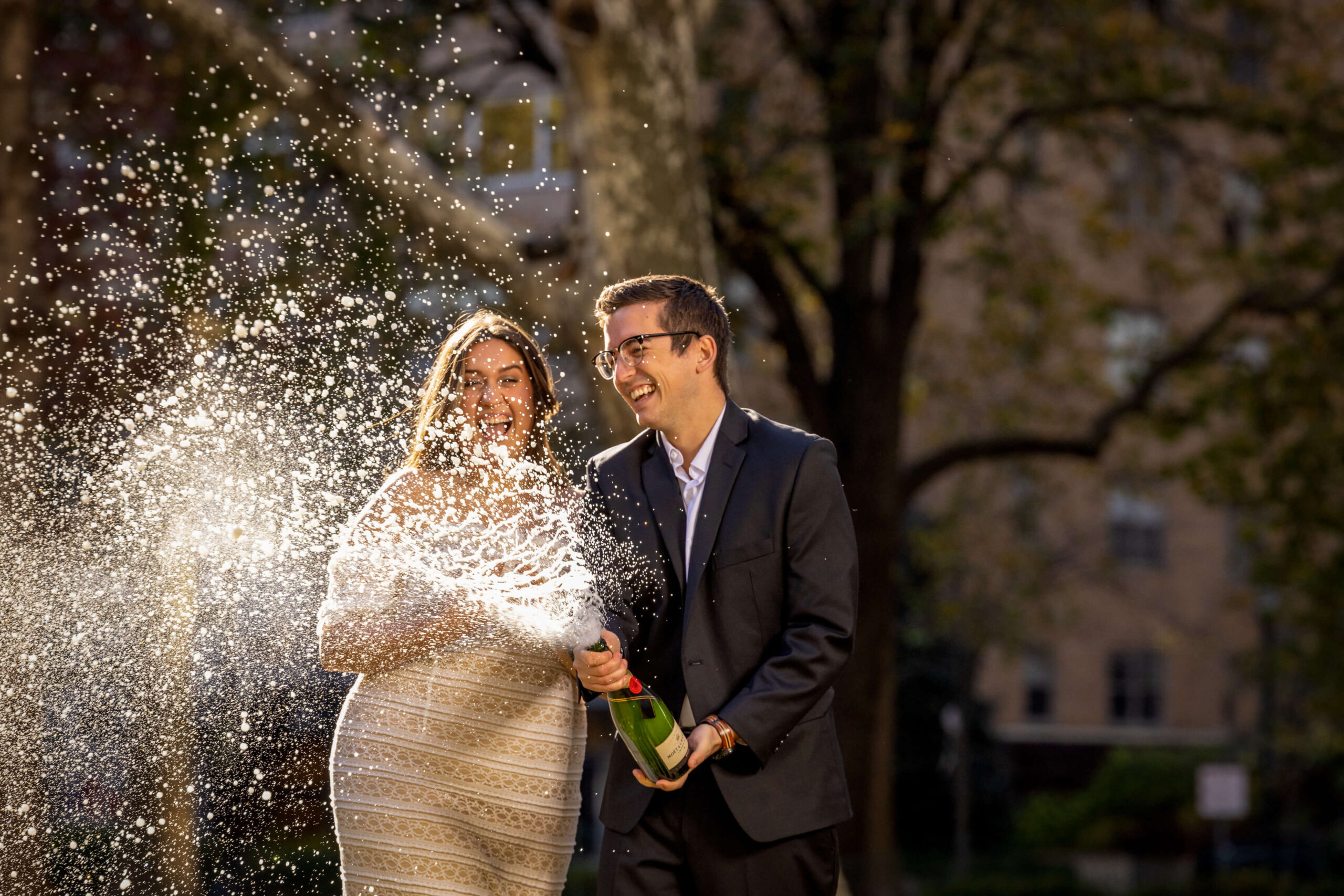 engaged couple popping champagne in rittenhouse square