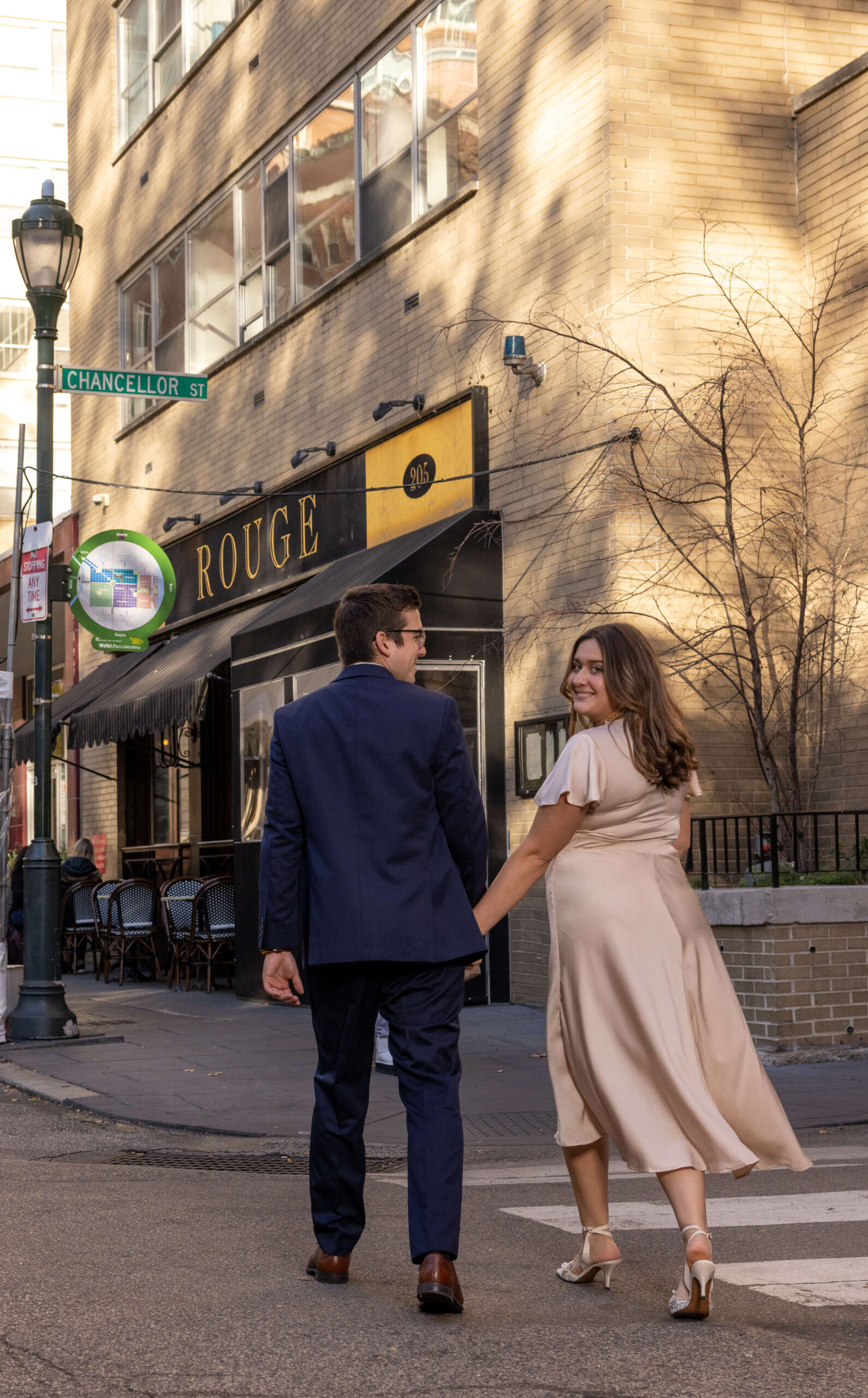 man and woman holding hands and walking over crosswalk