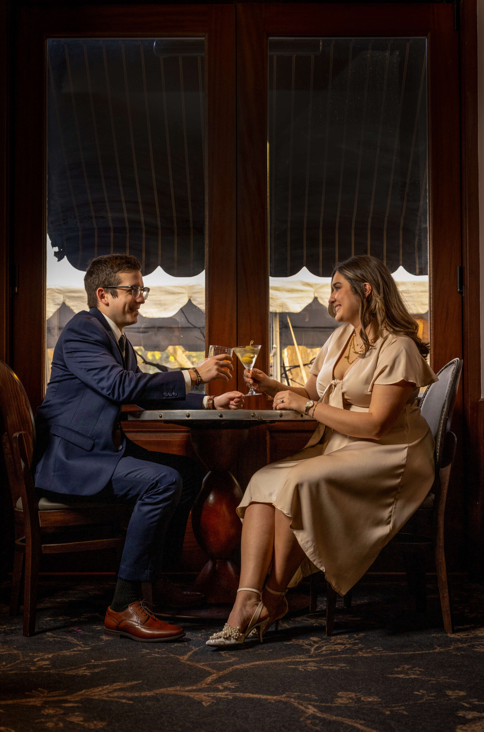 man and woman sharing cocktails by window at restaurant