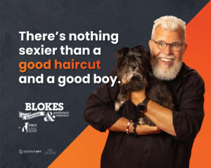 man with white hair smiling and holding a black dog