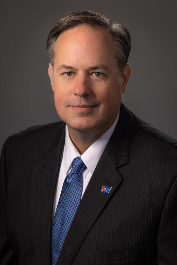 man with serious expression in black stripe suit with blue tie