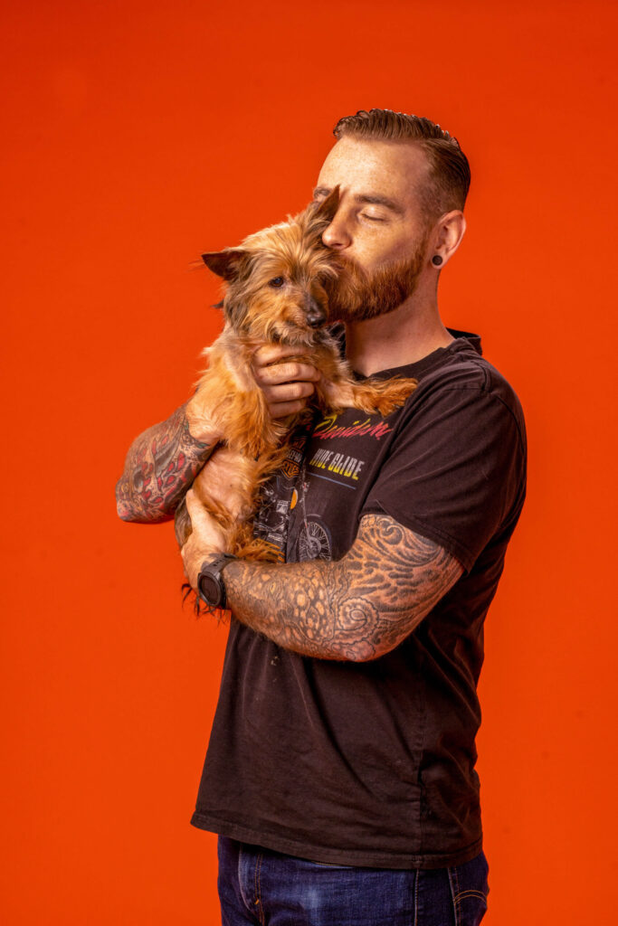 fun portrait photo of man kissing dog on cheek