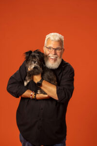 chuck gill voice posing with black dog